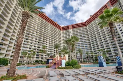 a large resort building with chairs and palm trees at Pineapple Paradise, Beach Front, Newly Renovated, Sleeps 6 in Panama City Beach