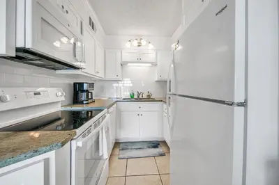 a white kitchen with white cabinets and a refrigerator at The Summit 431 in Panama City Beach