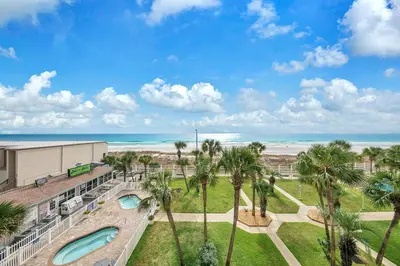 a view of the beach from the balcony of a resort with palm trees at The Summit 431 in Panama City Beach