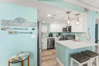 a kitchen with white cabinets and a blue wall at Sunbird 107E by InJoy Vacations in Panama City Beach