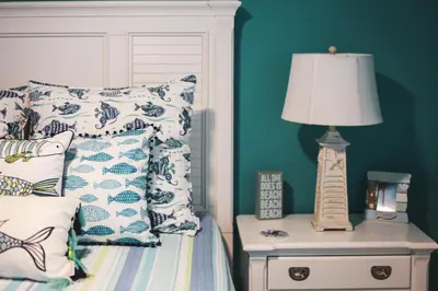 a bed with pillows and a lamp on a night stand at Sunbird 107E by InJoy Vacations in Panama City Beach