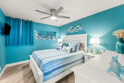 a blue bedroom with a bed and a ceiling fan at Sunbird 107E by InJoy Vacations in Panama City Beach