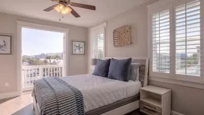 a bedroom with a bed with a ceiling fan and windows at Coconut Cove by AvantStay Deck w Hot Tub Access to 2 Pools in Santa Rosa Beach