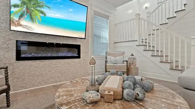 a living room with a table and a tv on the wall at Out of Office Beaches Private Pool Steps to Beach Sleeps 15 in Rosemary Beach