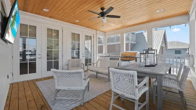 a screened porch with a table and chairs at Out of Office Beaches Private Pool Steps to Beach Sleeps 15 in Rosemary Beach