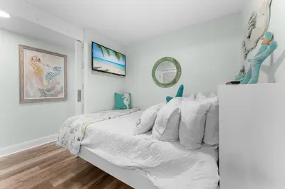 a white bedroom with a bed and a mirror at Modern Resort Condo! Gulf Views & Amenities Galore! presented by Dolce Vita Getaways! in Panama City Beach