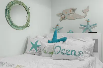 a bedroom with a bed with pillows and a mirror at Modern Resort Condo! Gulf Views & Amenities Galore! presented by Dolce Vita Getaways! in Panama City Beach