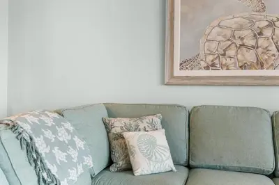 a green couch with pillows and a picture on the wall at Modern Resort Condo! Gulf Views & Amenities Galore! presented by Dolce Vita Getaways! in Panama City Beach