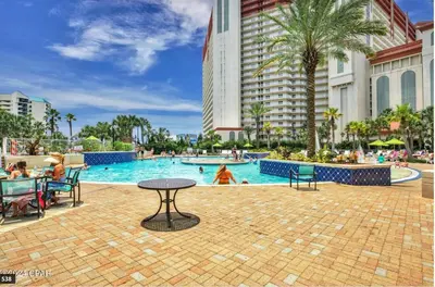 a pool at a resort with a table and chairs at Modern Resort Condo! Gulf Views & Amenities Galore! presented by Dolce Vita Getaways! in Panama City Beach