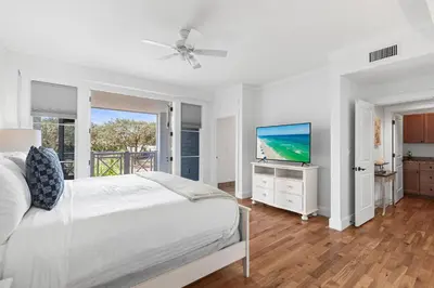 a white bedroom with a bed and a flat screen tv at Gulf Front- Large Pool- Watersound on 30A in Santa Rosa Beach