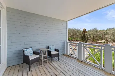 a patio with two chairs and a table on a deck at Gulf Front- Large Pool- Watersound on 30A in Santa Rosa Beach