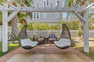 a backyard with two chairs and a pergola at 6-Seater Golf Cart - Community Pool - Close to Beach, Dining and Shopping in Inlet Beach