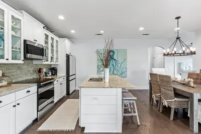 a kitchen with white cabinets and a wooden table at 6-Seater Golf Cart - Community Pool - Close to Beach, Dining and Shopping in Inlet Beach