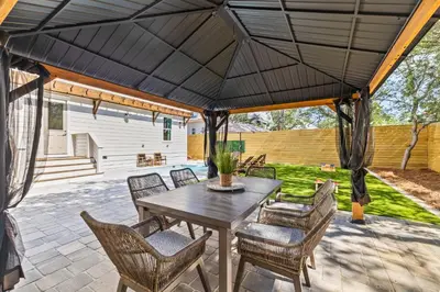 a patio with a table and chairs under a black umbrella at Golf Cart-Private Pool and Hot Tub-Close to Beach in Santa Rosa Beach