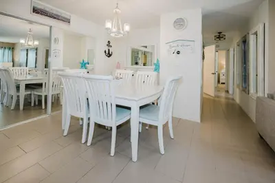 a white dining room with a white table and chairs at Beach House That Sleeps 14 With Pool, Gym, Beach Access in Panama City Beach