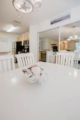 a kitchen and dining room with a white table and chairs at Beach House That Sleeps 14 With Pool, Gym, Beach Access in Panama City Beach