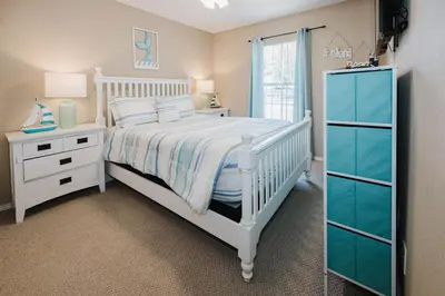 a white bedroom with a bed and a dresser at Beach House That Sleeps 14 With Pool, Gym, Beach Access in Panama City Beach