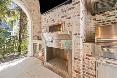an outdoor kitchen with a brick wall and an oven at Tranquility on the Preserve in Watersound Beach