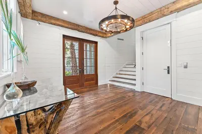 a hallway with wood floors and a door and a chandelier at Tranquility on the Preserve in Watersound Beach