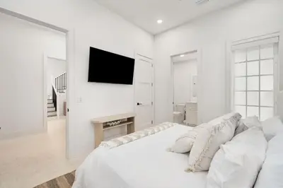 a white bedroom with a bed and a flat screen tv at No More Cloudy Days in Santa Rosa Beach