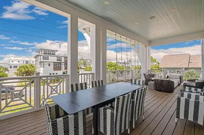 a porch with a table and chairs on a balcony at No More Cloudy Days in Santa Rosa Beach