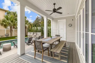 a patio with a table and chairs and a pool at Breezy Blue in Santa Rosa Beach