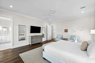 a white bedroom with a bed and a flat screen tv at Breezy Blue in Santa Rosa Beach