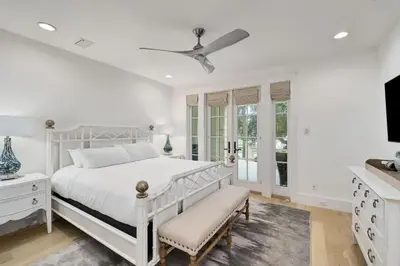 a white bedroom with a white bed and a tv at Sunset at 409 in Watersound Beach