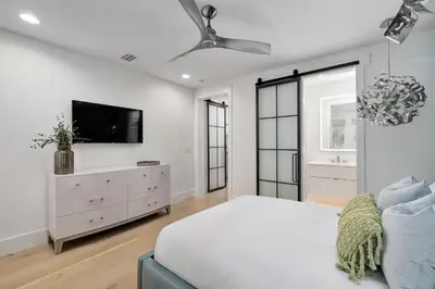 a white bedroom with a bed and a tv at Sunset at 409 in Watersound Beach