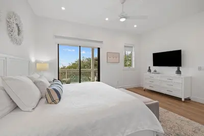 a white bedroom with a large bed and a television at Eyes on Sunrise in Seacrest