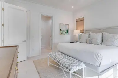 a white bedroom with a large bed and a bench at Coastal Comfort in Seacrest