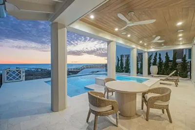 a patio with a table and chairs and a pool at Selah at the Sea in Santa Rosa Beach