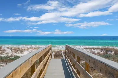 a boardwalk to the beach with the ocean in the background at Selah at the Sea in Santa Rosa Beach