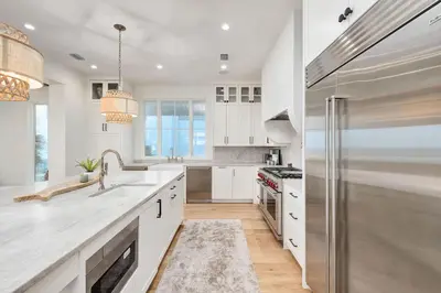 a kitchen with white cabinets and a stainless steel refrigerator at Selah at the Sea in Santa Rosa Beach