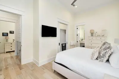 a white bedroom with a bed and a flat screen tv at Belle La Mer in Inlet Beach