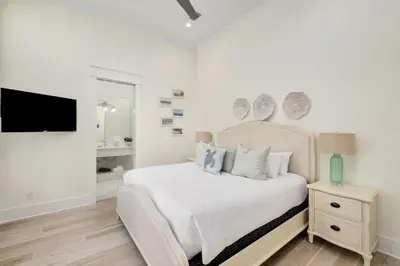 a white bedroom with a bed and a flat screen tv at Belle La Mer in Inlet Beach