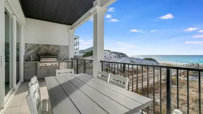 a porch with a table and chairs and the ocean at Azzurro Moon in Seagrove Beach