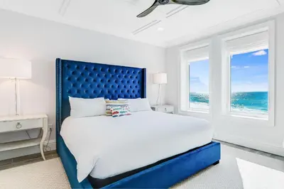 a bedroom with a large bed with a blue headboard at Azzurro Sky in Seagrove Beach