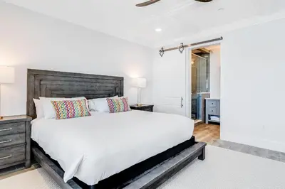 a bedroom with a large white bed with a wooden headboard at Azzurro Sky in Seagrove Beach
