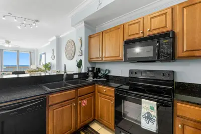 a kitchen with wooden cabinets and a black appliances at 1002 Sunrise Beach in Panama City Beach
