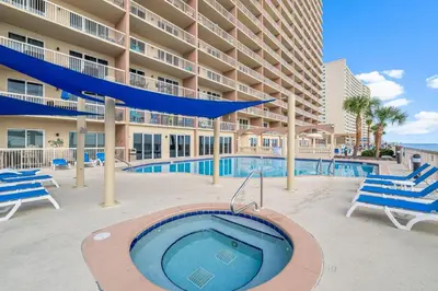a swimming pool with chairs and a building at 1002 Sunrise Beach in Panama City Beach