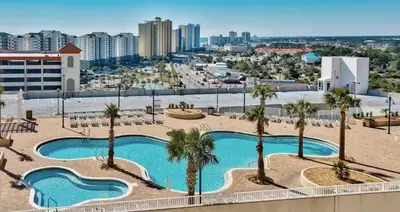 a pool with palm trees and a city in the background at Panama City -3 Bedroom - Laketown Wharf in Panama City Beach