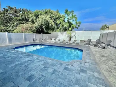a swimming pool with chaises and chairs next to a fence at Majestic View Beach House in Panama City Beach