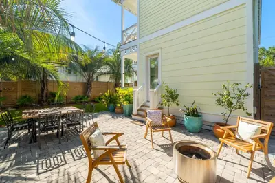 a patio with a table and chairs and a house at 30A Beach House - Under the Palms by Panhandle Getaways in Santa Rosa Beach
