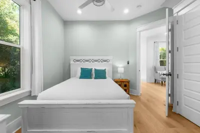a white bedroom with a white bed with blue pillows at 30A Beach House - Under the Palms by Panhandle Getaways in Santa Rosa Beach