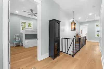 a living room with a ceiling fan and a black cabinet at 30A Beach House - Under the Palms by Panhandle Getaways in Santa Rosa Beach