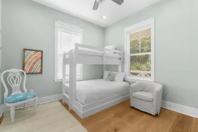 a bedroom with a white bunk bed and a chair at 30A Beach House - Under the Palms by Panhandle Getaways in Santa Rosa Beach