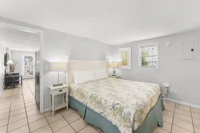 a bedroom with a large bed and a white wall at Island Time Bungalow in Panama City Beach