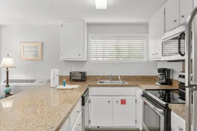 a kitchen with white cabinets and a counter top at Island Time Bungalow in Panama City Beach