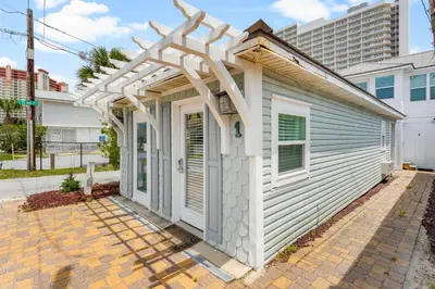 a white house with an arbor over the door at Island Time Bungalow in Panama City Beach